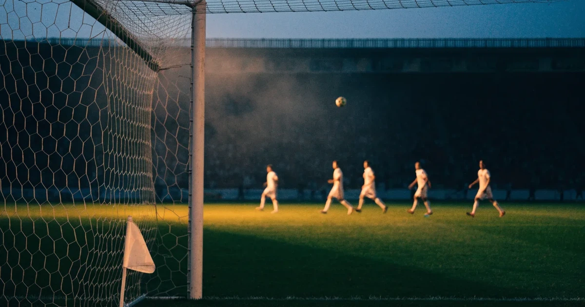 Blick durch ein Stadiontor auf einen grünen Rasen im Abendlicht, ein Ball ruht an der Eckfahne, die Tribünen sind leer.