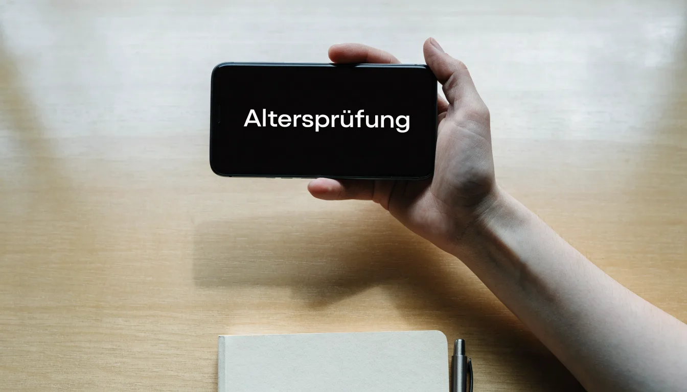 Eine Messingwaage und ein geschlossenes Buch stehen auf einem hellen Tisch vor einer ruhigen, unscharfen Wand.